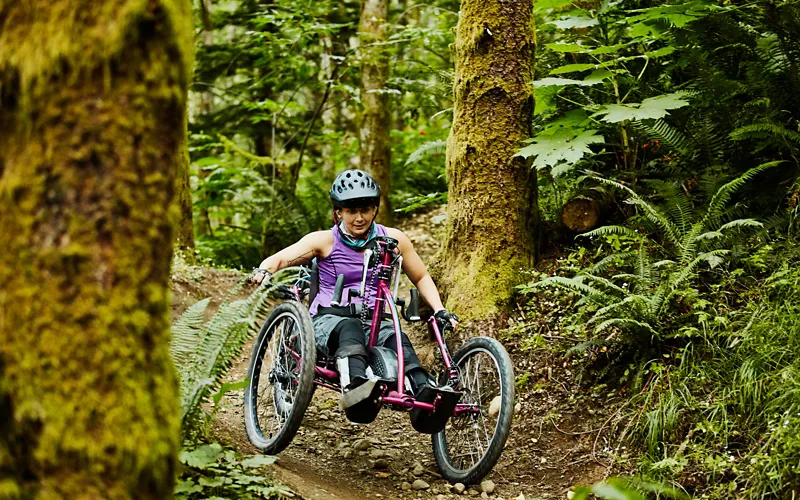 Un'atleta in sedia a rotelle su un sentiero in un bosco