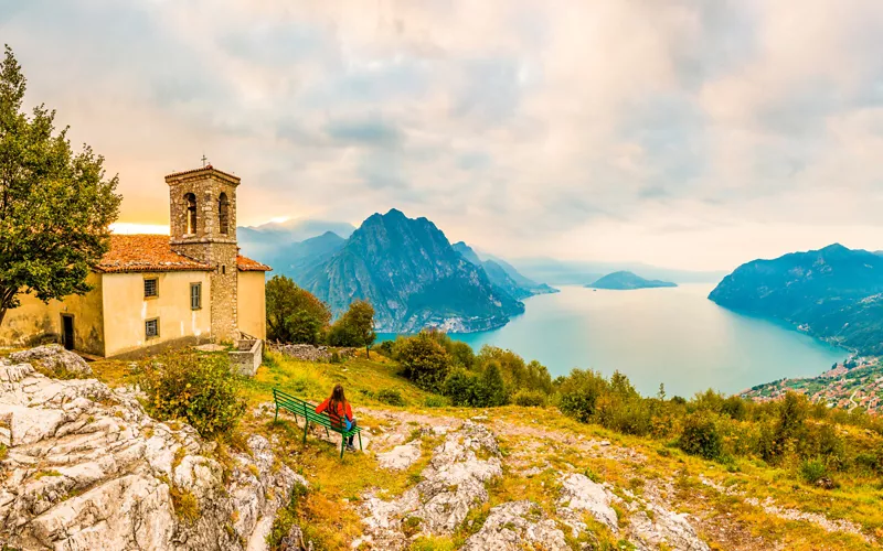 Mujer en un banco frente al lago Iseo en Lombardía