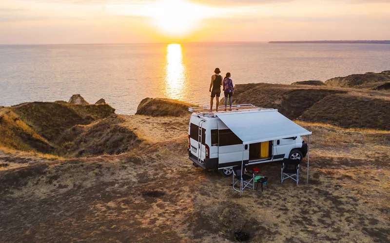 Due ragazzi sul tetto di un camper al tramonto