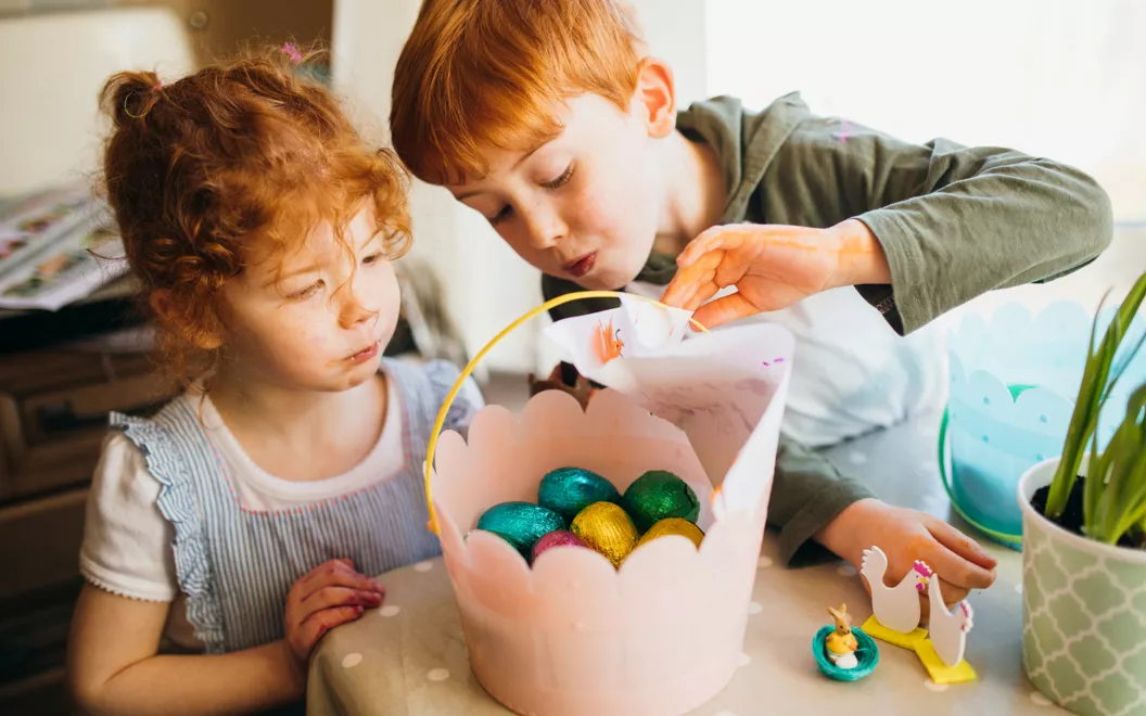 Dos niños con una cesta de huevos de Pascua