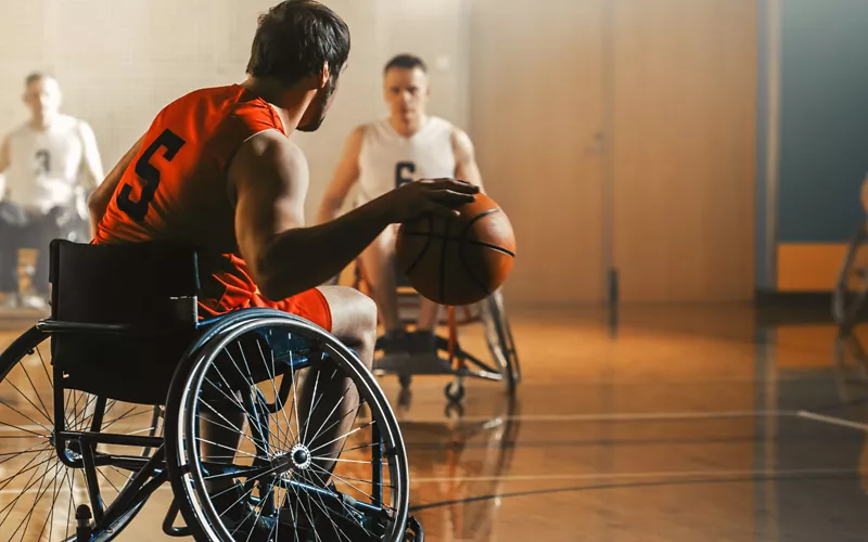 Dei ragazzi in sedia a rotelle che giocano a pallacanestro