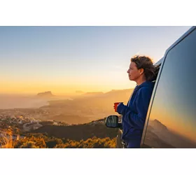 A woman admiring the landscape from a camper