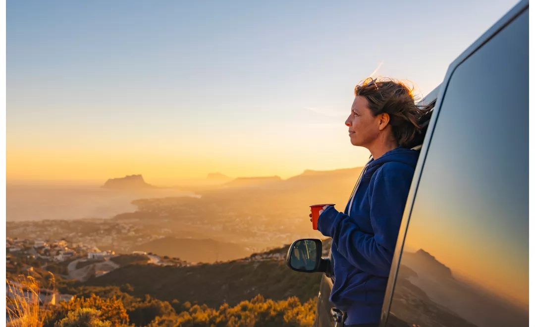 A woman admiring the landscape from a camper