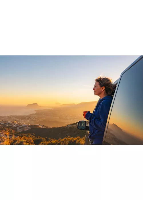Una mujer admira el paisaje desde una autocaravana