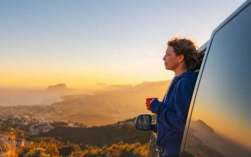 Una mujer admira el paisaje desde una autocaravana
