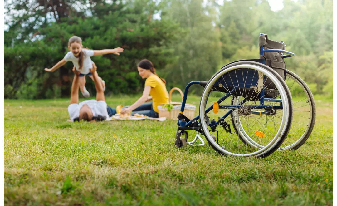Una famiglia al parco e una sedia a rotelle