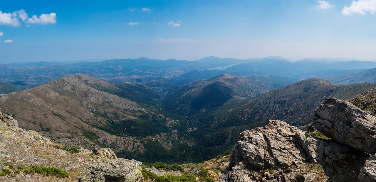 Panoramic view from Punta La Marmora highest mountain peak at Gennargentu mountain in Sardinia, Nuoro, Italy. Vaste peaks, dry plains and valleys with mediterranean vegetation. Late summer, blue sky