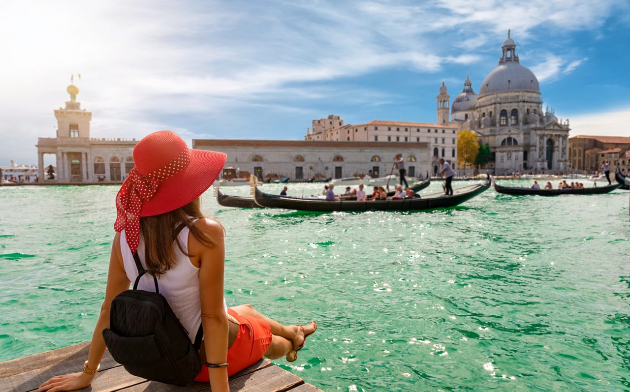Attractive, female tourist enjoys the view to the Basilica di Santa Maria della Salute and Canale Grande in Venice, Italy