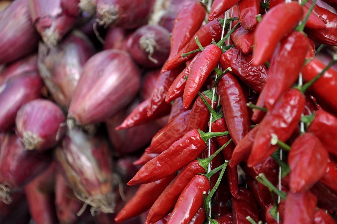 Close-up of two calabrian specialities: Chili pepper and the famous red tropea onion "cipolla rossa di Tropea". Both very important goods of the local economy and tourist magnet.