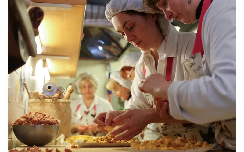 Una donna prepara dei tortellini a mano in un laboratorio di pasta fresca