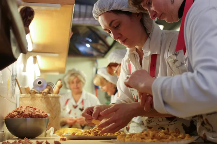 Una donna prepara dei tortellini a mano in un laboratorio di pasta fresca