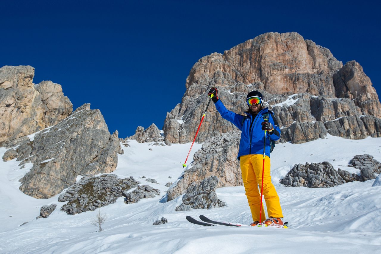 Alpine skier stand on slope in winter mountains Dolomities Italy in beautiful alps Cortina d'Ampezzo Cinque torri mountain peaks famous landscape skiing resort area