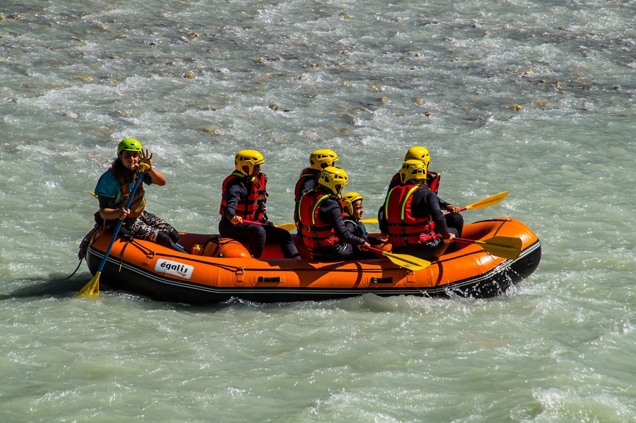 AOSTA, ITALY - Oct 02, 2020: The people rafting on the flowing wavy Dora Baltea River in Ital
