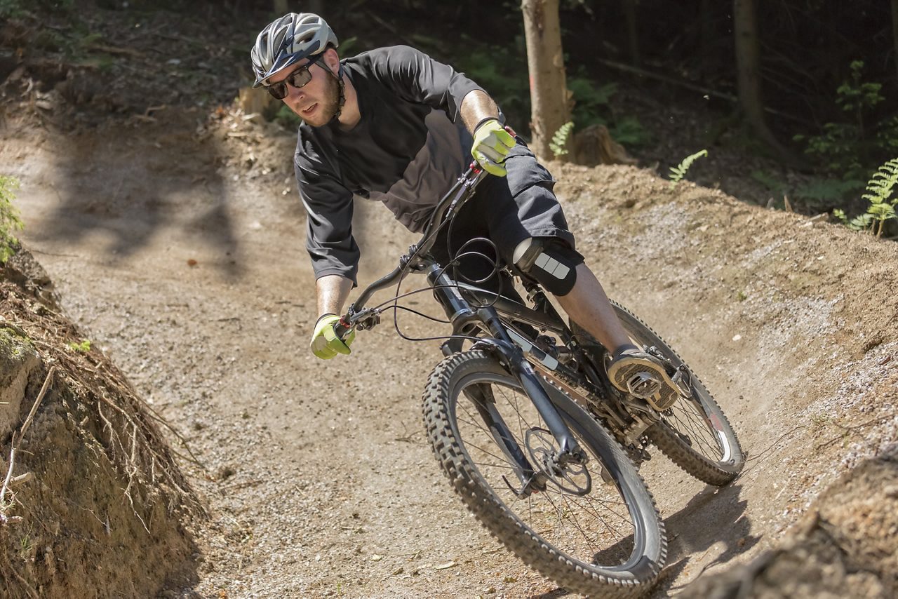 Mountain bike rider rides through a gravity slope of an artificial dirt track. The scene is held in earthy colors.