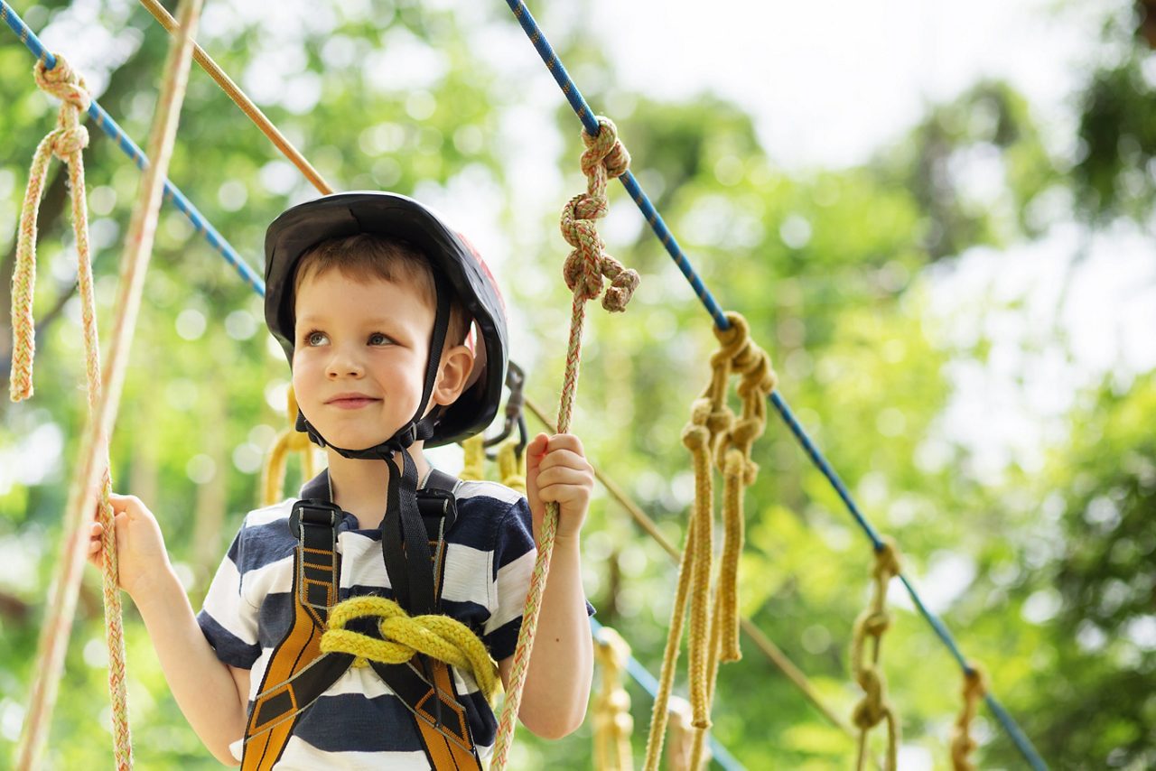 Boy enjoys climbing in the ropes course adventure park