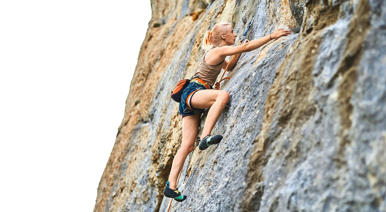 young woman rock climber Climbing The Rock Having Workout In Mountains, searching, reaching and gripping hold on white background. outdoors rock climbing and active lifestyle concept.