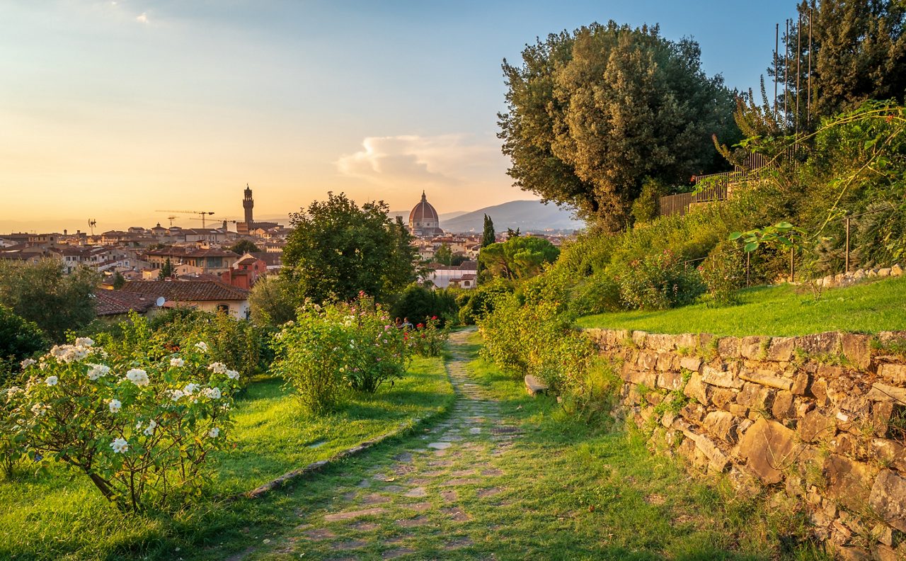 Romantic Florence, Italy seen from Giardino delle rose park. Italian landscape with rose bushes, grass, rocks and trees. Skyline with Duomo, Cathedral of Santa Maria del Fiore, Brunelleschi's Dome.