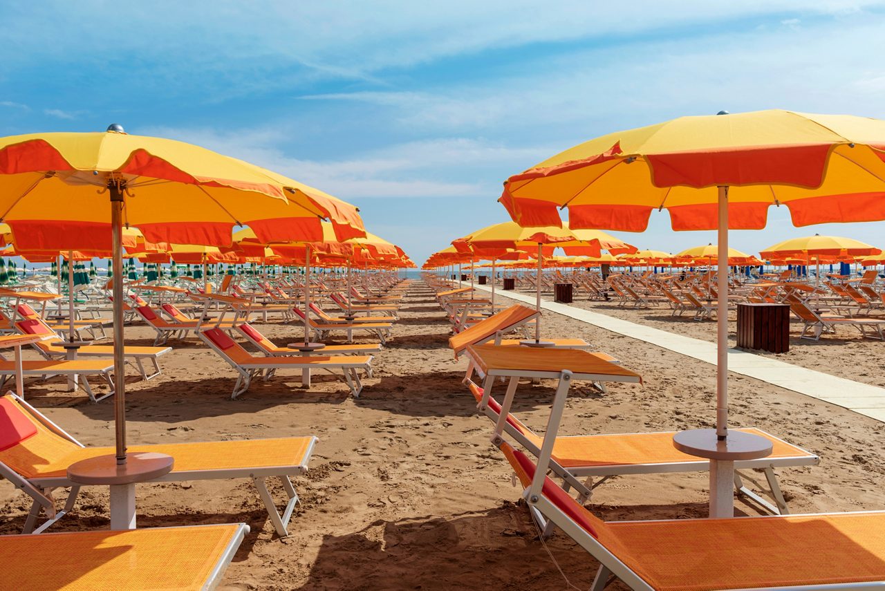 Bright orange umbrellas and sun loungers on the beach in Rimini, Italy. 