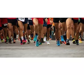 Foto delle gambe di maratoneti che corrono su strada.