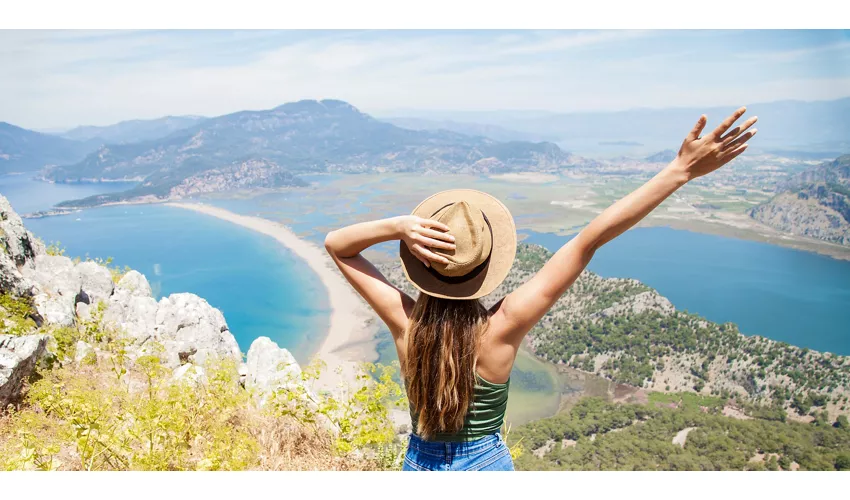 Happy woman with hands up standing on cliff over sea and islands at summer. Vintage mood, concepts of winner, freedom, happiness etc.
