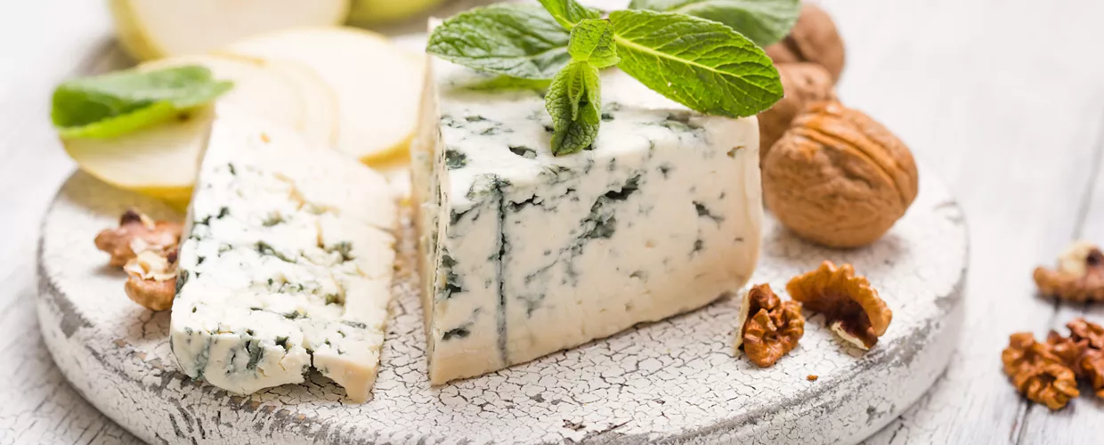 Segment of blue mould cheese - Gorgonzola with pear and walnuts on wooden board.  Top view